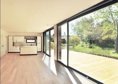 Moderner Wohn- und Essbereich mit Küche und großer Glasfront mit Schiebetüren in den Garten